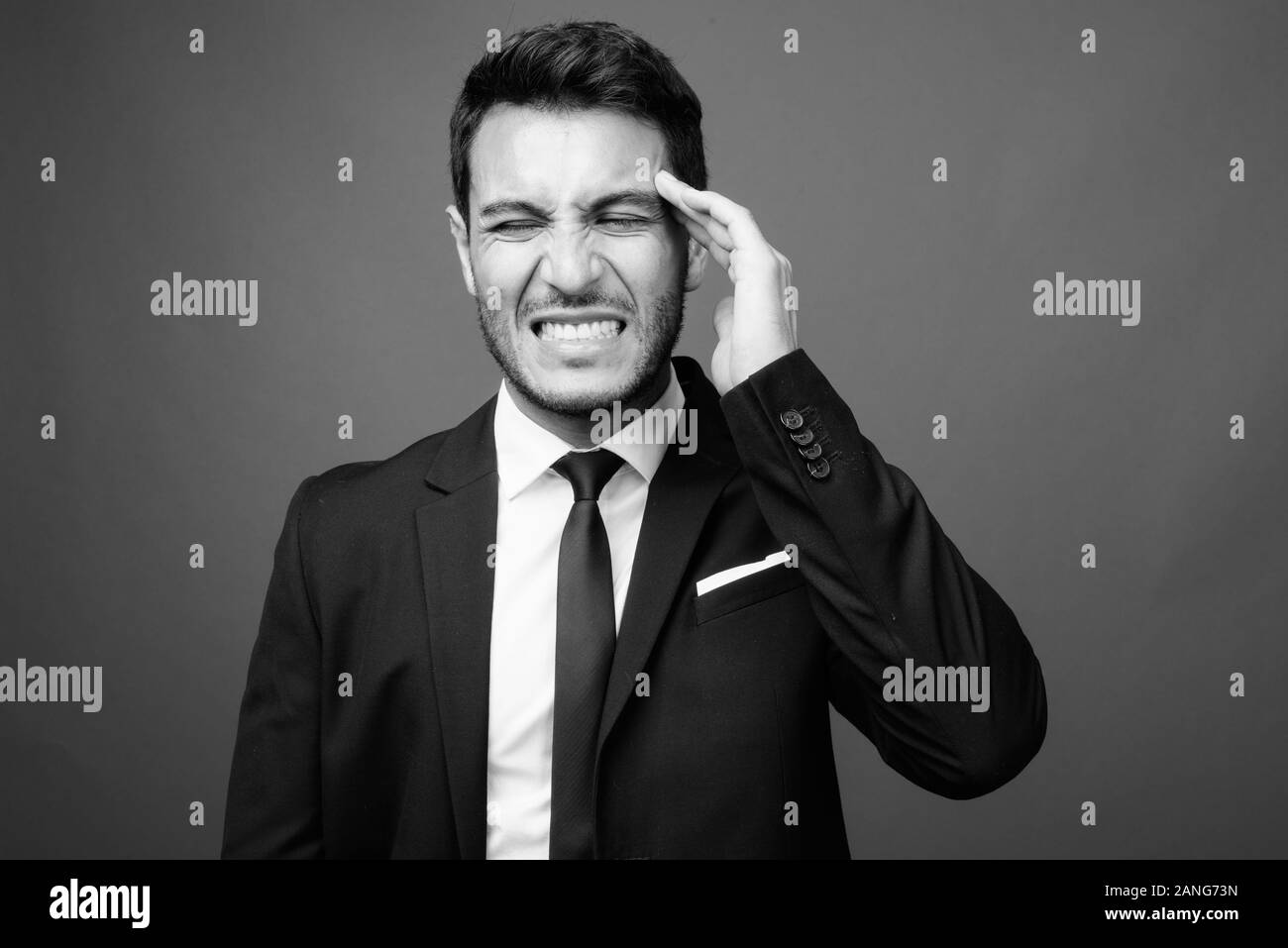Bel giovane imprenditore ispanica contro uno sfondo grigio Foto Stock
