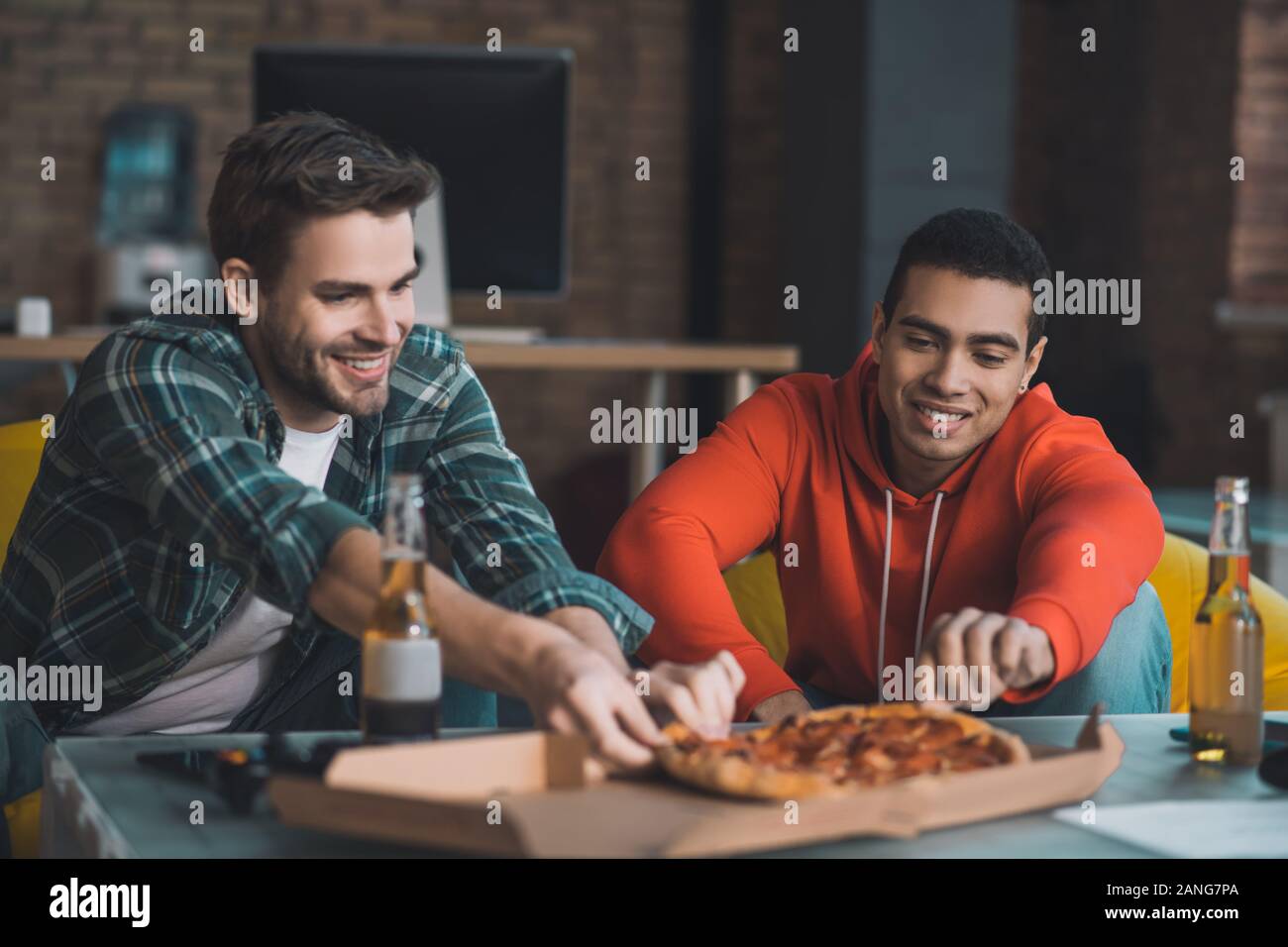 Gioiosa felici uomini di mangiare la pizza a casa Foto Stock