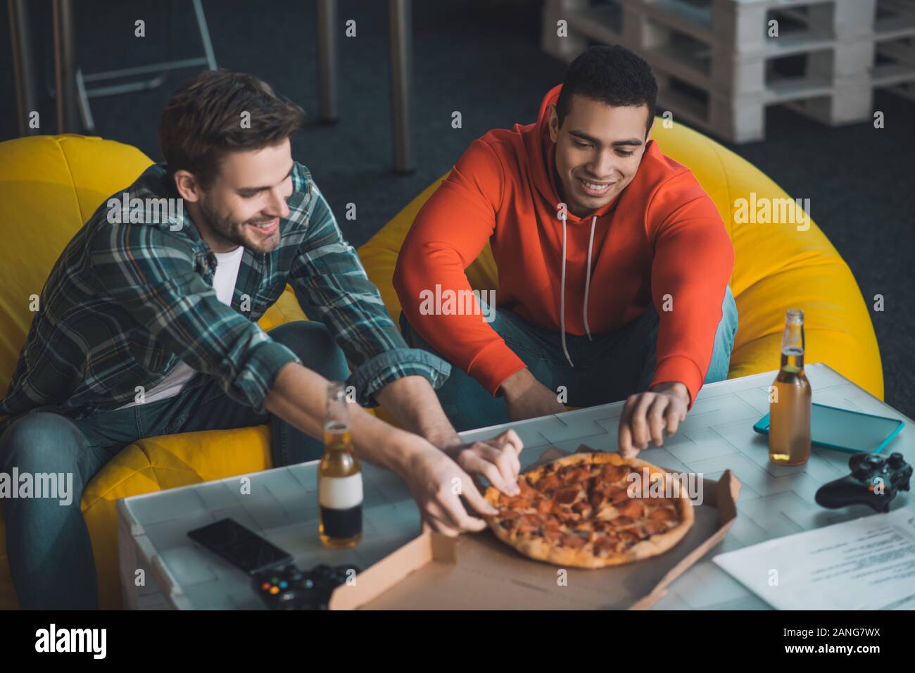 Belli gli uomini affamati prendendo pezzi di pizza Foto Stock