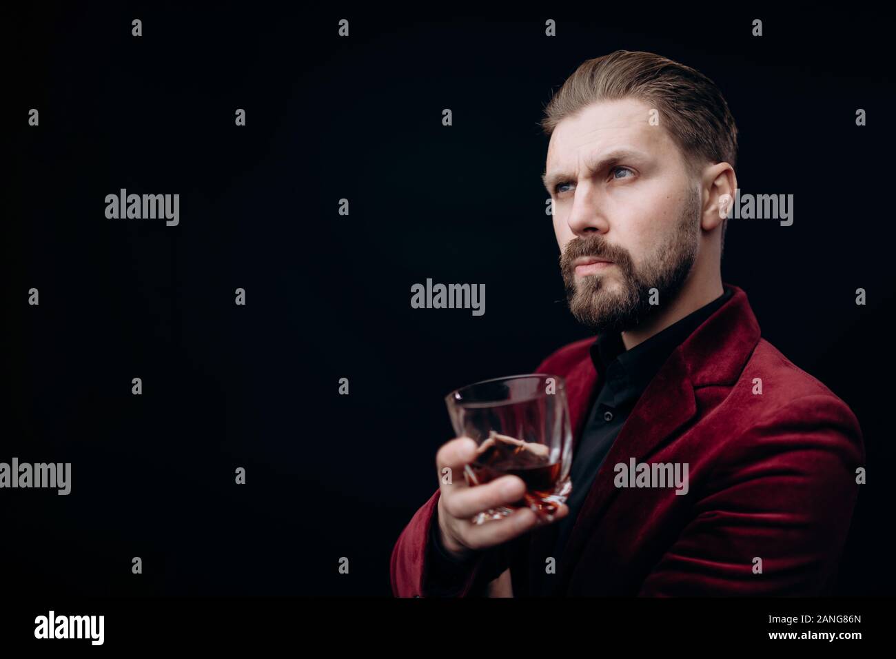 Bel maschio virile in camicia di Vinica tenendo un bicchiere di bevande spiritose Foto Stock