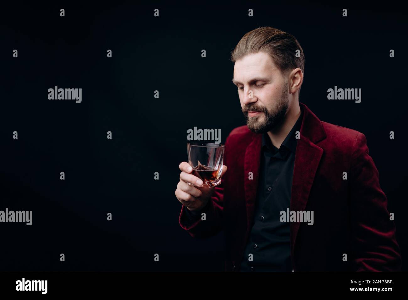 Elegante uomo in giacca in velluto guardando i suoi drink Foto Stock