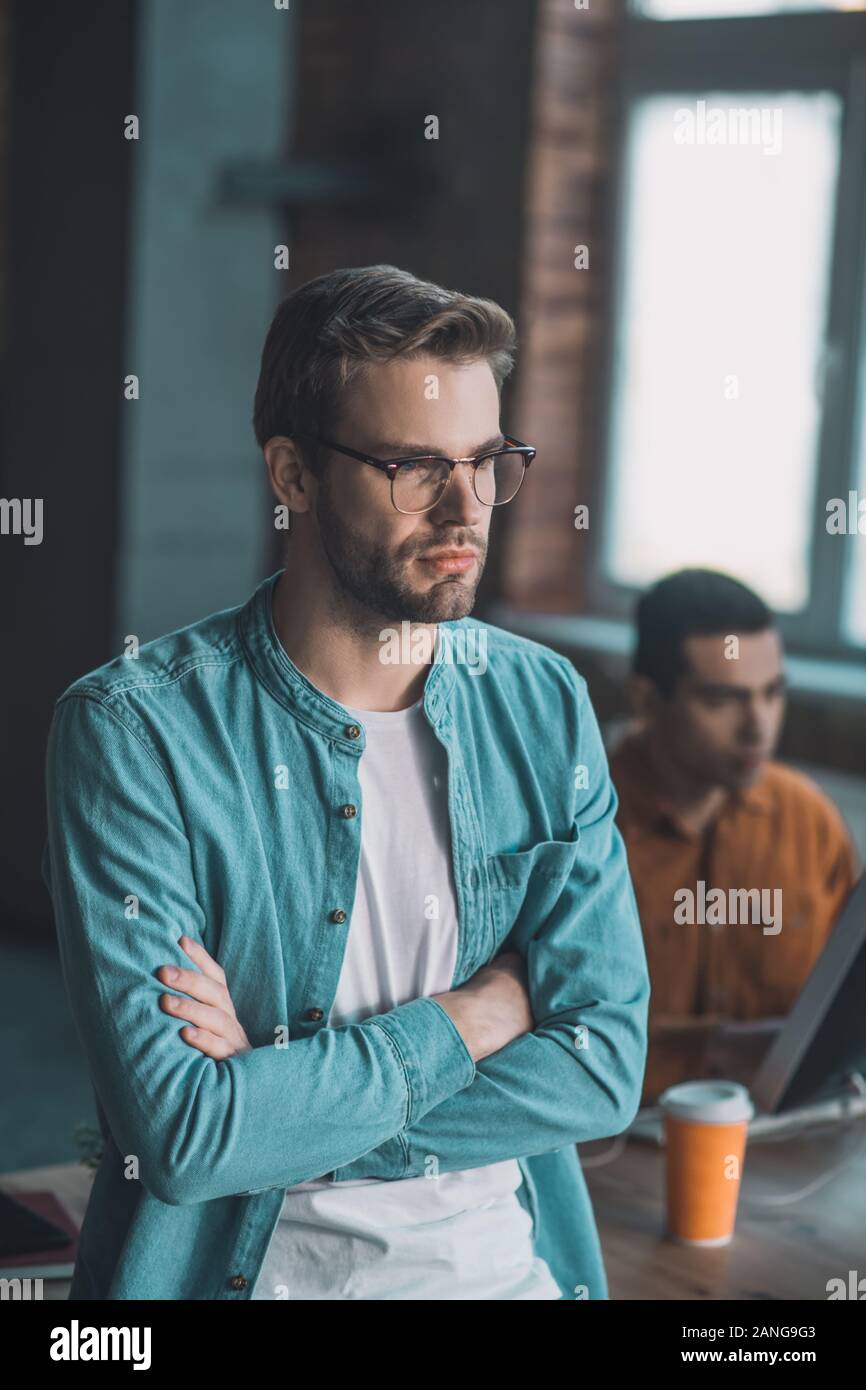 Giovane serio in piedi con le sue mani incrociate Foto Stock