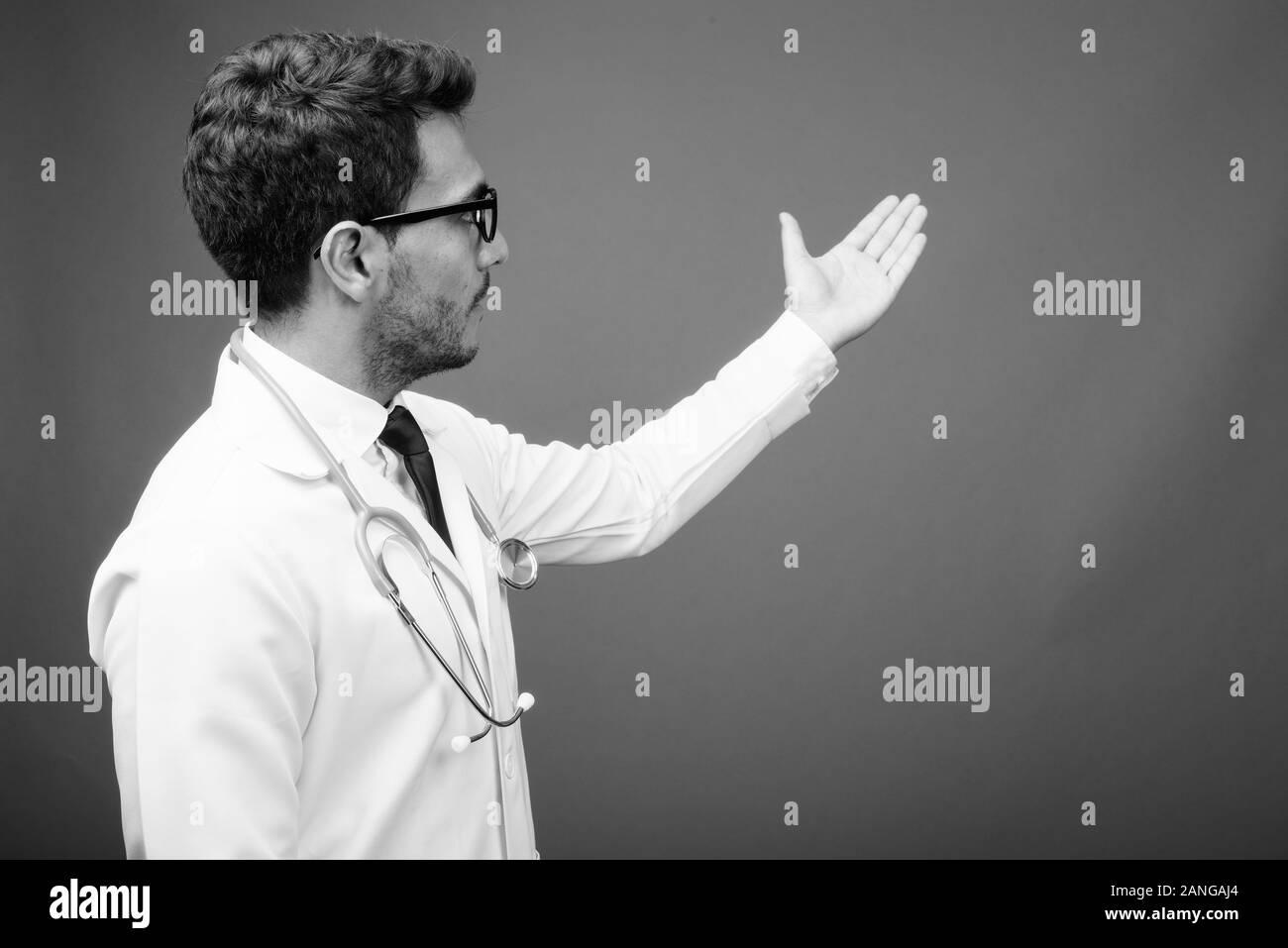 Bel giovane uomo ispanico medico contro uno sfondo grigio Foto Stock