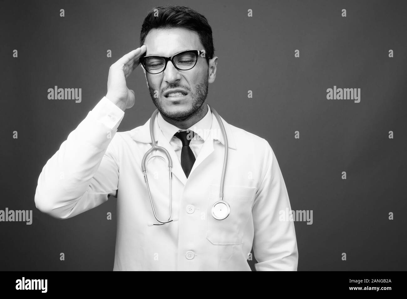 Bel giovane uomo ispanico medico contro uno sfondo grigio Foto Stock