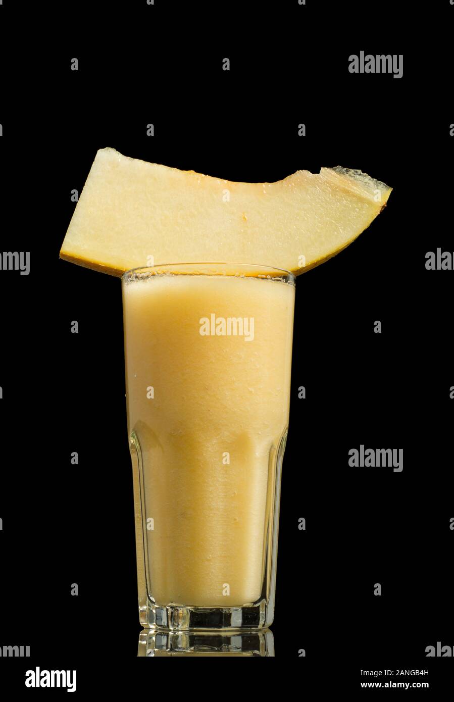 Bicchiere di delizioso frullato di melone con fette di melone dolce isolato su gackground nero Foto Stock