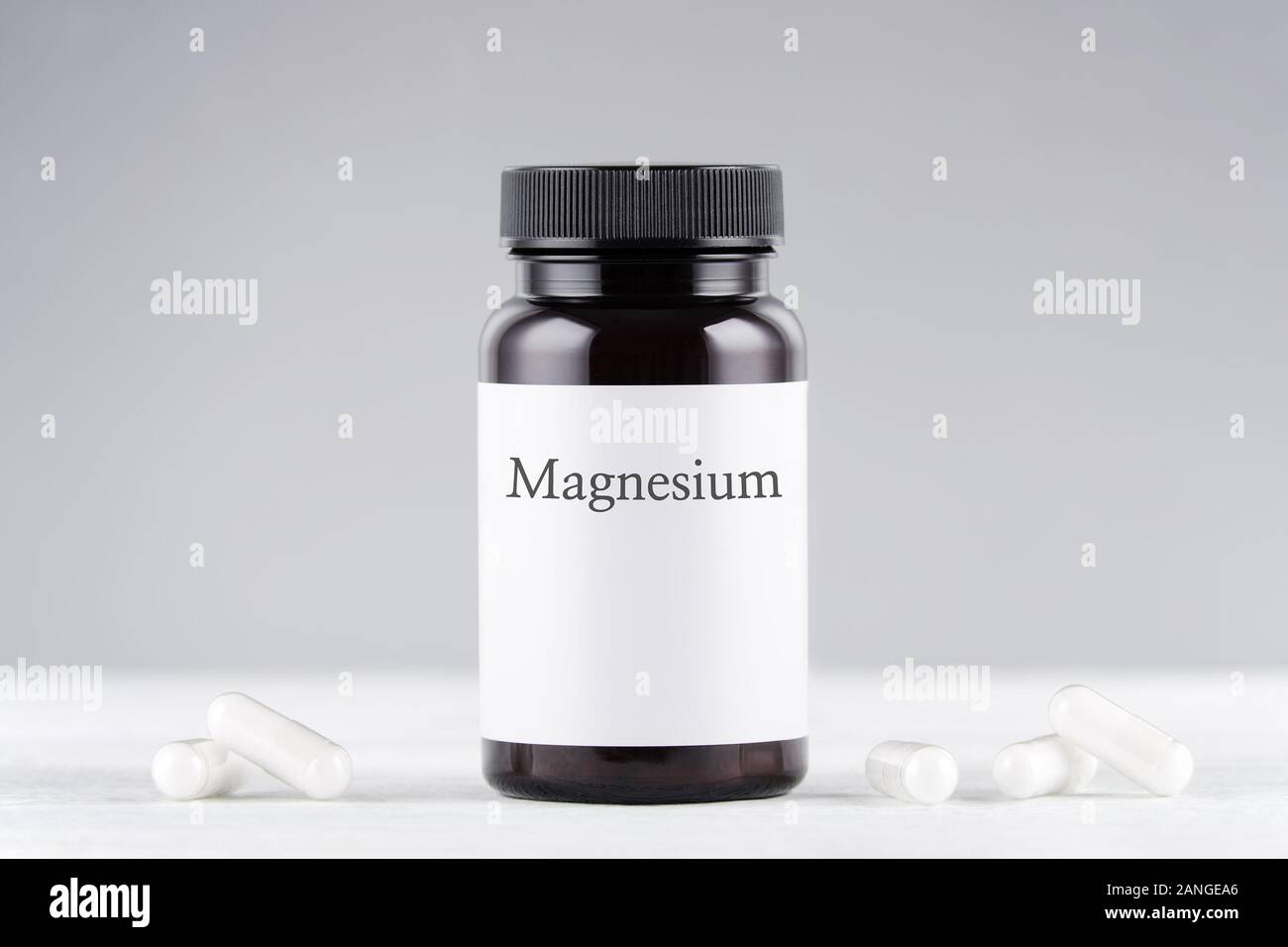 Supplemento nutrizionale bottiglia di magnesio e capsule su grigio Foto Stock