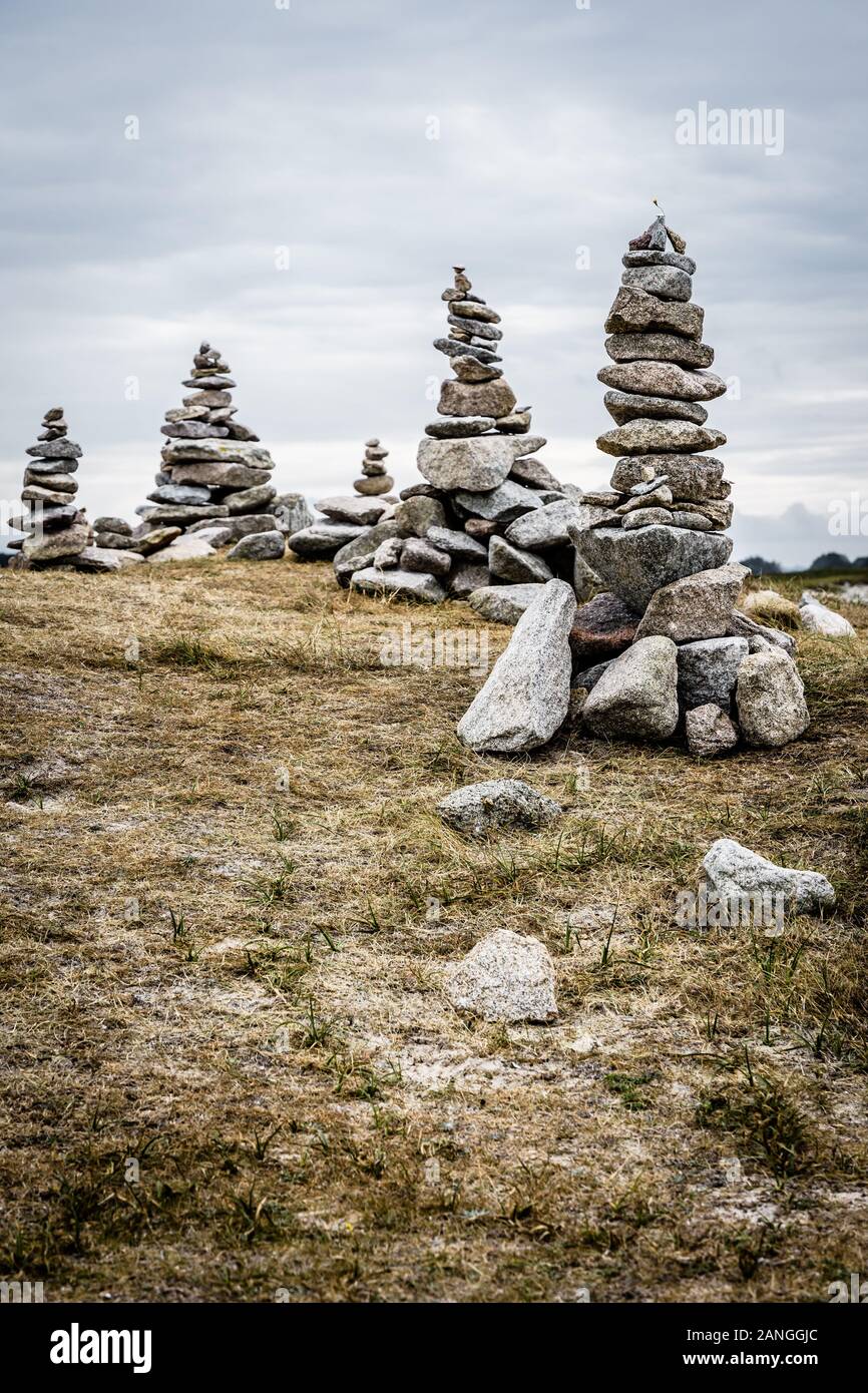 Diversi artificiali in pietra in granito di pile (chiamato cairns) sul sentiero costiero in Bretagna, Francia, in un giorno nuvoloso. Foto Stock