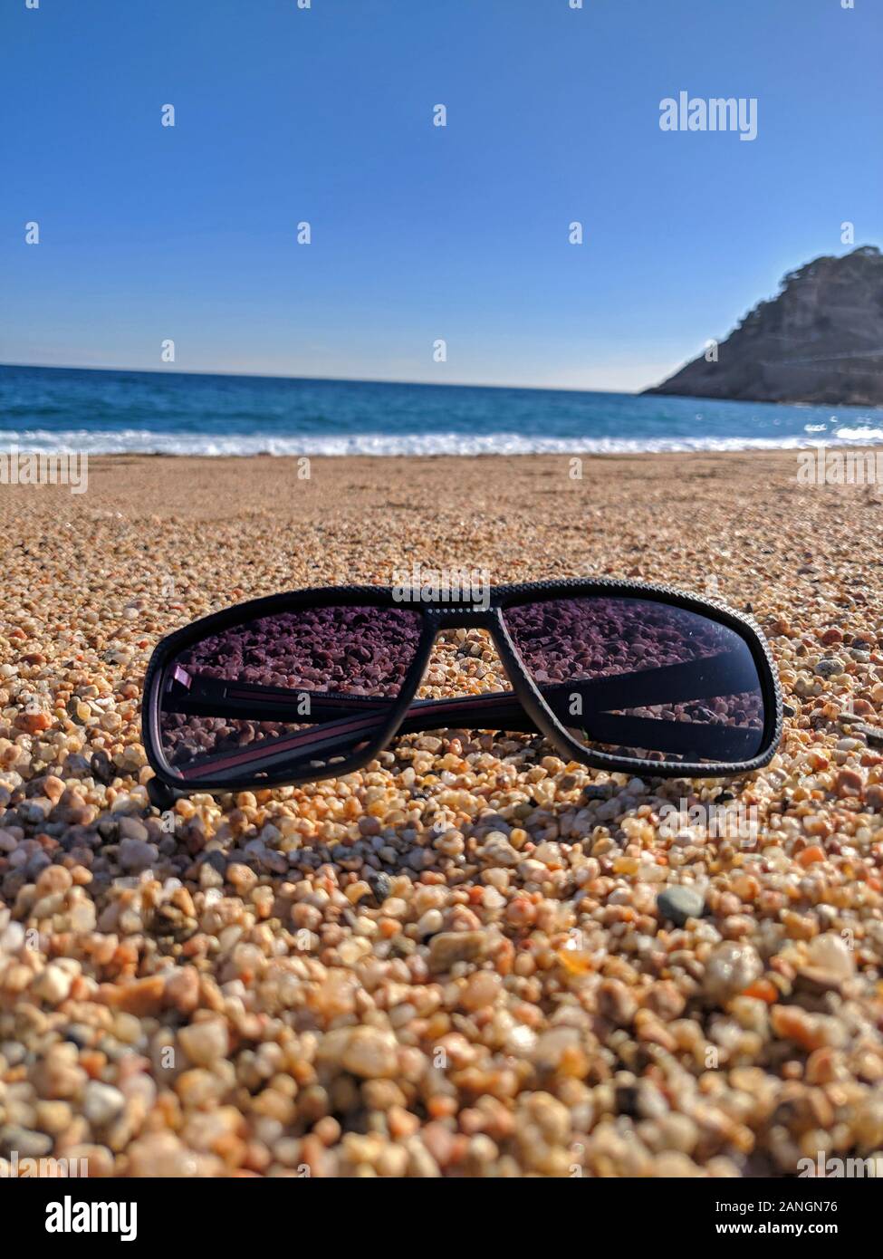 Occhiali da sole su ciottoli con fondale di acqua Foto Stock