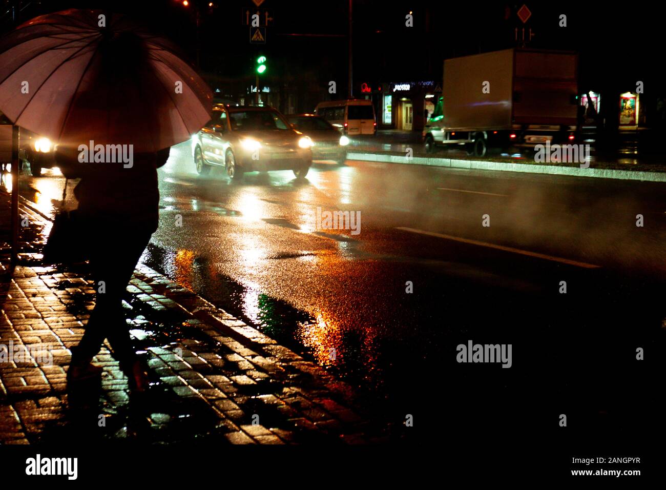 Serata piovosa. Una silhouette di donna con ombrello e in funzione del traffico con gocce di pioggia. Tempo d'autunno. Hight ISO Foto Stock