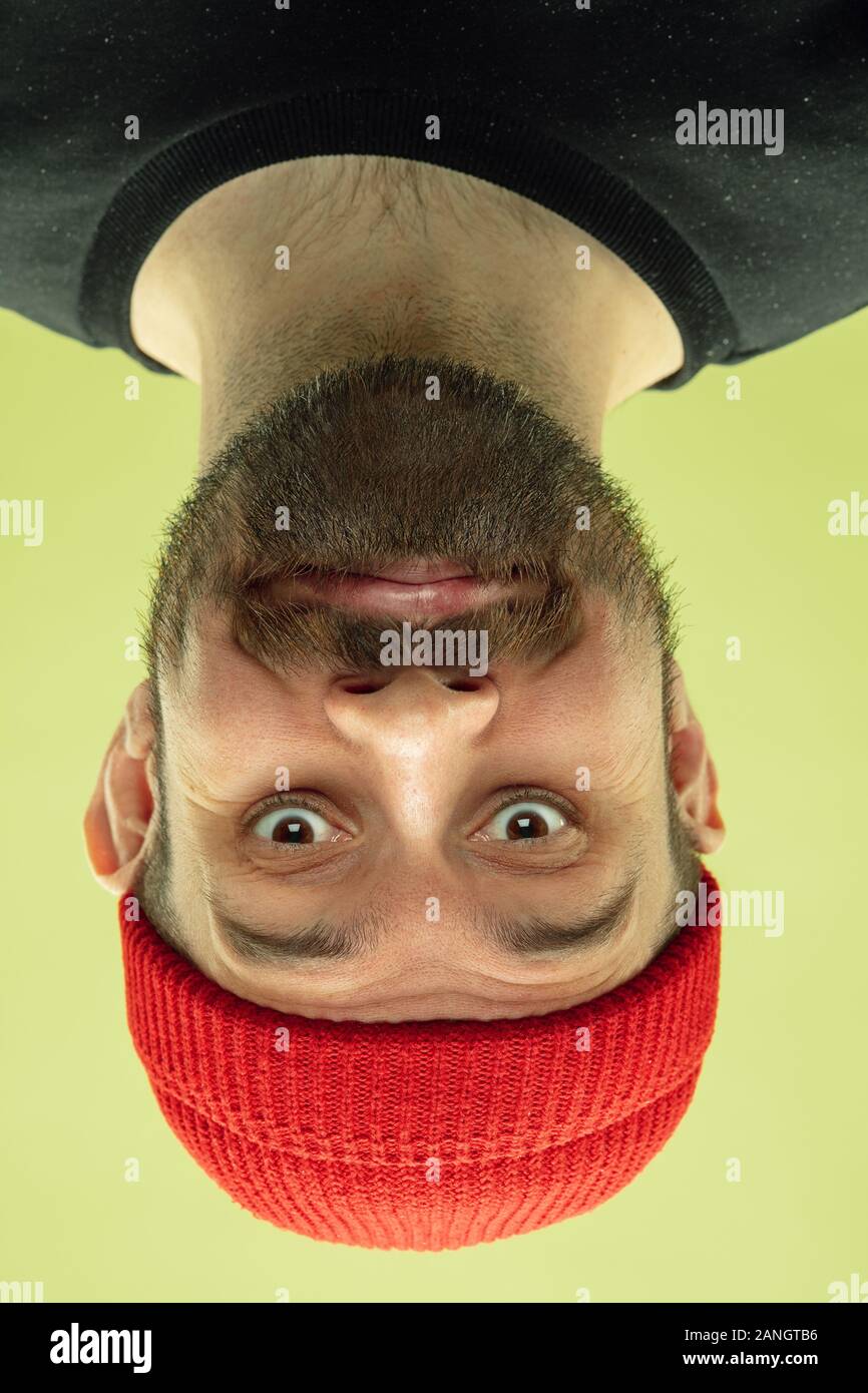 Carino sorridente. Verticale invertito di soggetti di razza caucasica giovane uomo su giallo di sfondo per studio. Le emozioni umane non sono quello che sembrano quando stai guardando. L'espressione del viso, funny view, pubblicità. Foto Stock