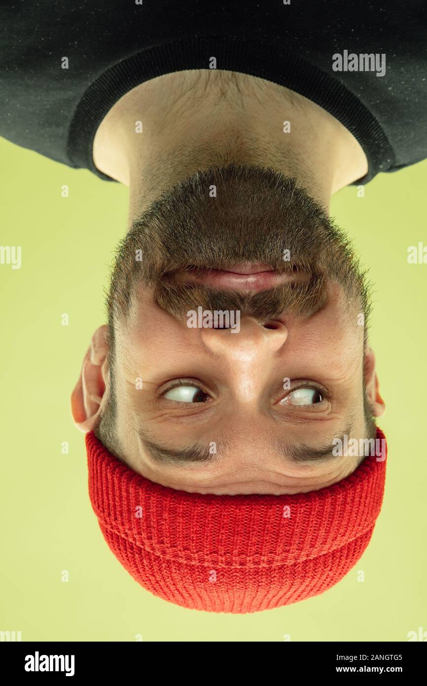 Carino sorridente, guardando a lato. Verticale invertito di soggetti di razza caucasica giovane uomo su giallo di sfondo per studio. Le emozioni umane non sono quello che sembrano quando stai guardando. L'espressione del viso, divertente, pubblicità. Foto Stock