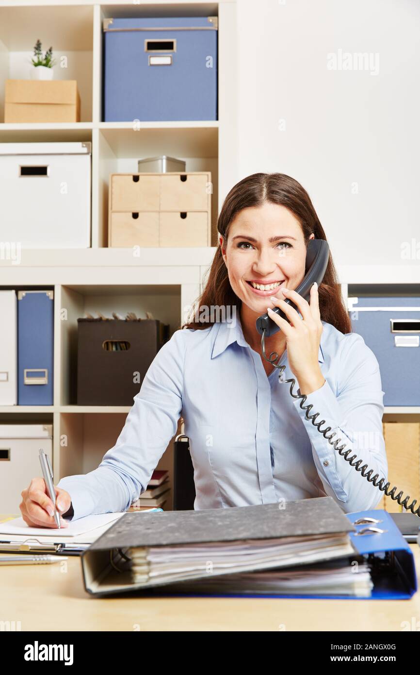 Donna sorridente in ufficio sta chiamando il numero verde del servizio di assistenza clienti Foto Stock