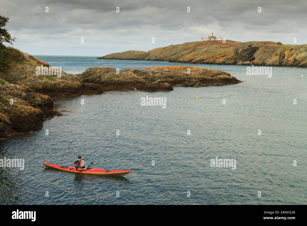 Sea kayaker guardando verso Point Lynas faro in Anglesey North Wales Foto Stock