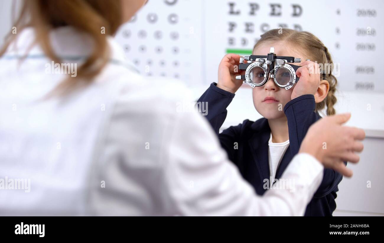 Pretty Little Schoolgirl visita oculista per la misurazione della vista con phoropter Foto Stock