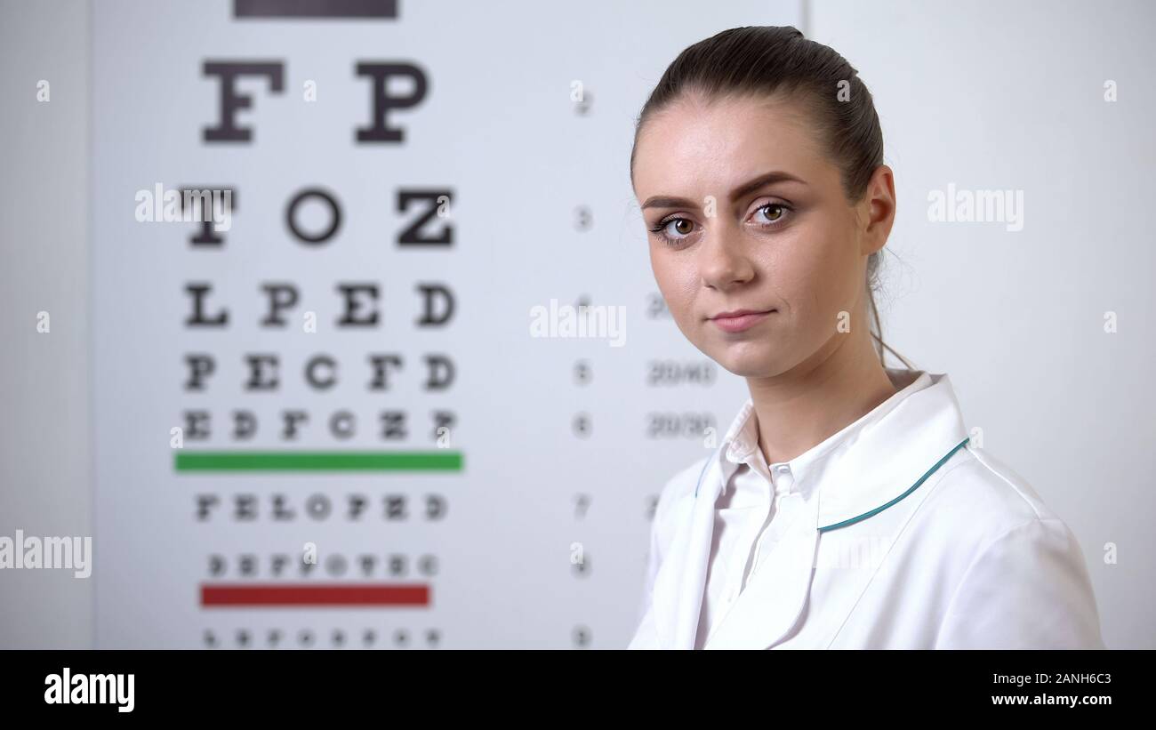Ottico femmina in piedi vicino al grafico oculare, diagnostica di vision clinic, salute Foto Stock