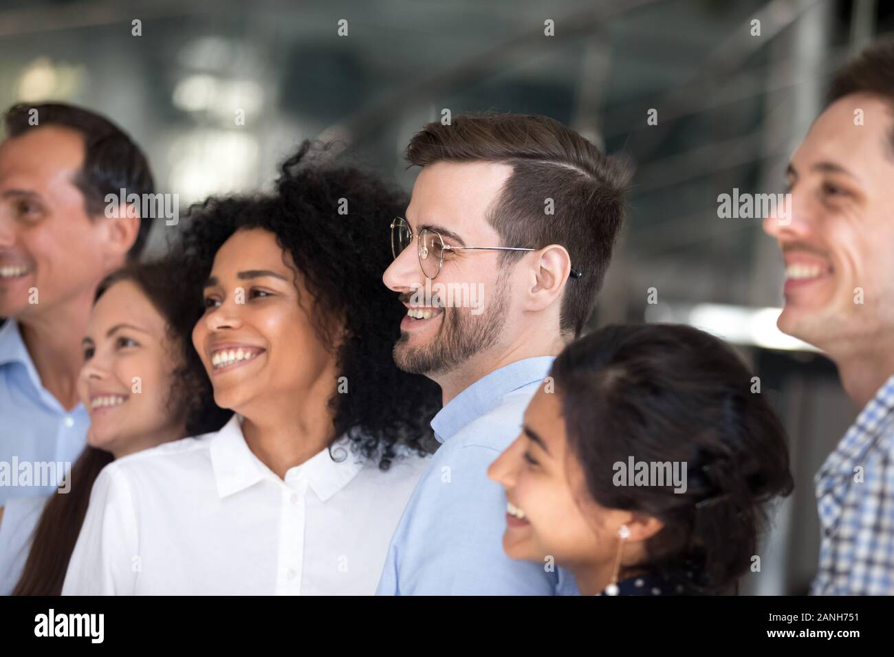 E multirazziale i colleghi millenario stand in fila sorridente che posano per una foto di gruppo, eccitato giovane diverse persone si radunano fare foto del team, motivata per sh Foto Stock