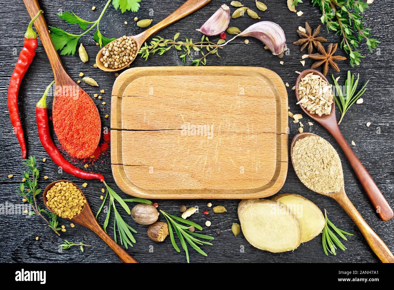 Telaio della piastra, cucchiai con pepe macinato, fieno greco, zenzero e coriandolo, rametti di rosmarino fresco, il timo e il prezzemolo, baccelli di peperoncino, cardamomo, un Foto Stock