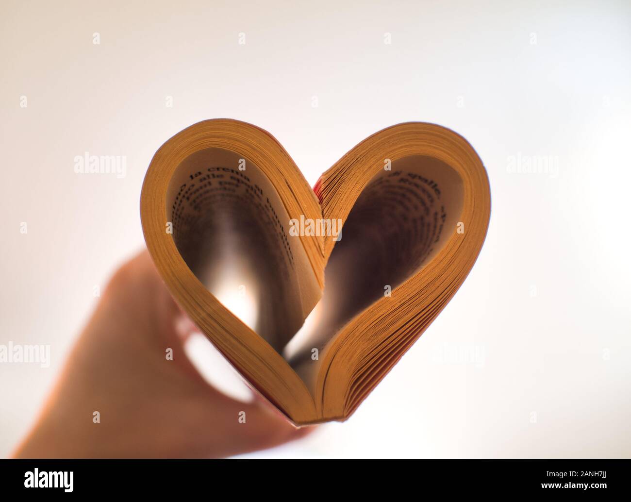 Cuore dalle pagine di un libro con la mano Foto Stock