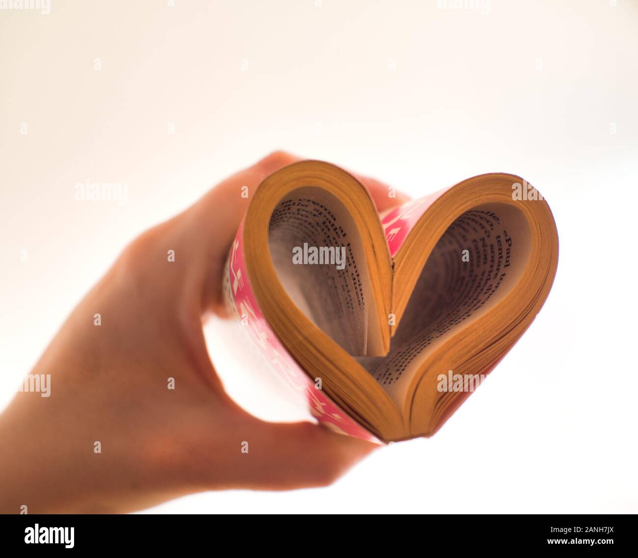 Cuore dalle pagine di un libro con la mano Foto Stock