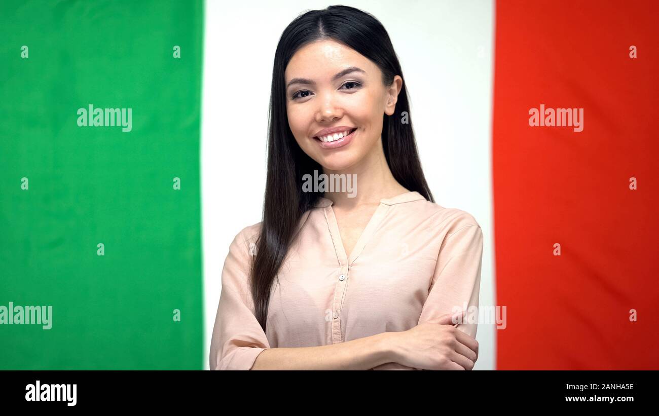 Fiducioso donna che guarda la telecamera contro la bandiera italiana sullo sfondo, cittadinanza Foto Stock
