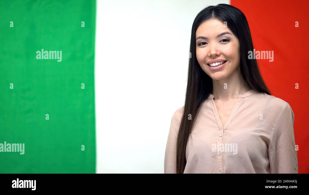 Positivo donna sorridente contro la bandiera italiana sullo sfondo, agenzia di traduzione Foto Stock