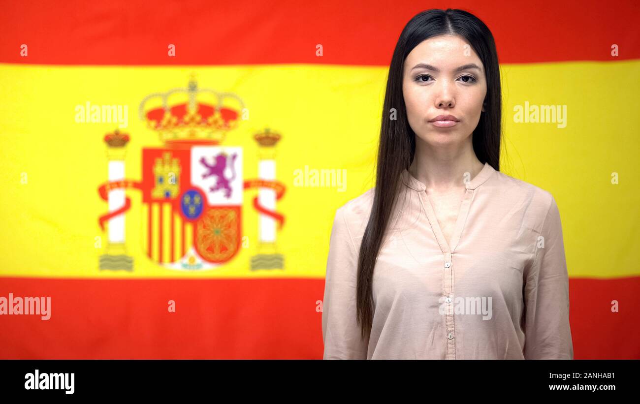 Femmina fiducioso guardando la telecamera, Spanish flag di sfondo, il controllo del passaporto Foto Stock