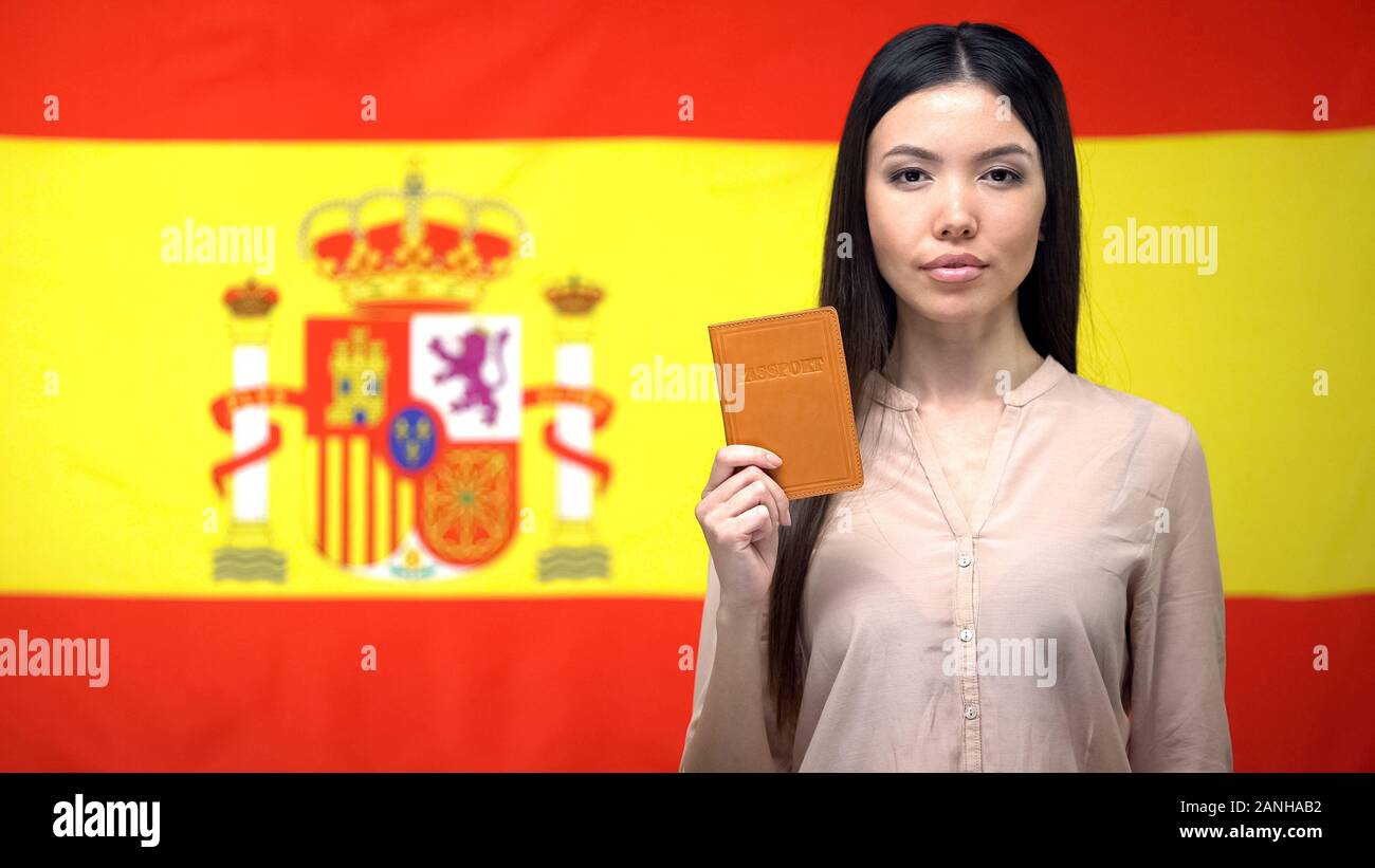 Grave donna asiatica mostrando passaporto contro Spanish flag di sfondo, la migrazione Foto Stock