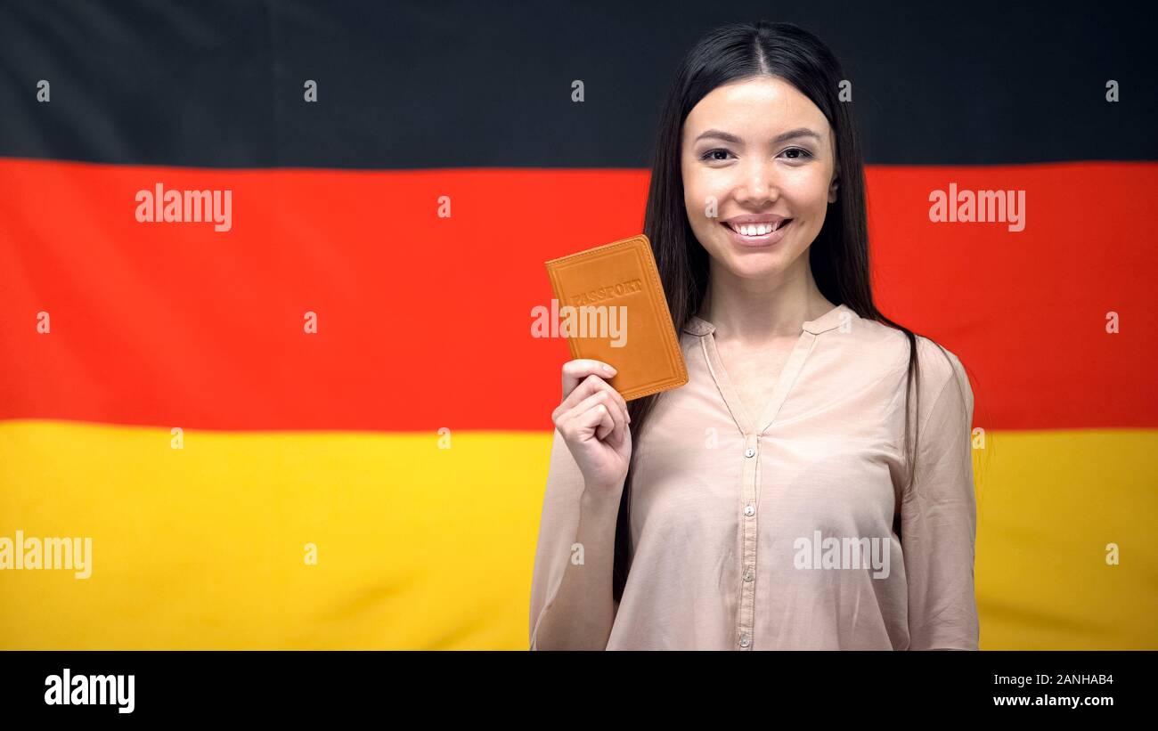 Donna sorridente holding passaporto contro bandiera tedesca sfondo, la migrazione Foto Stock