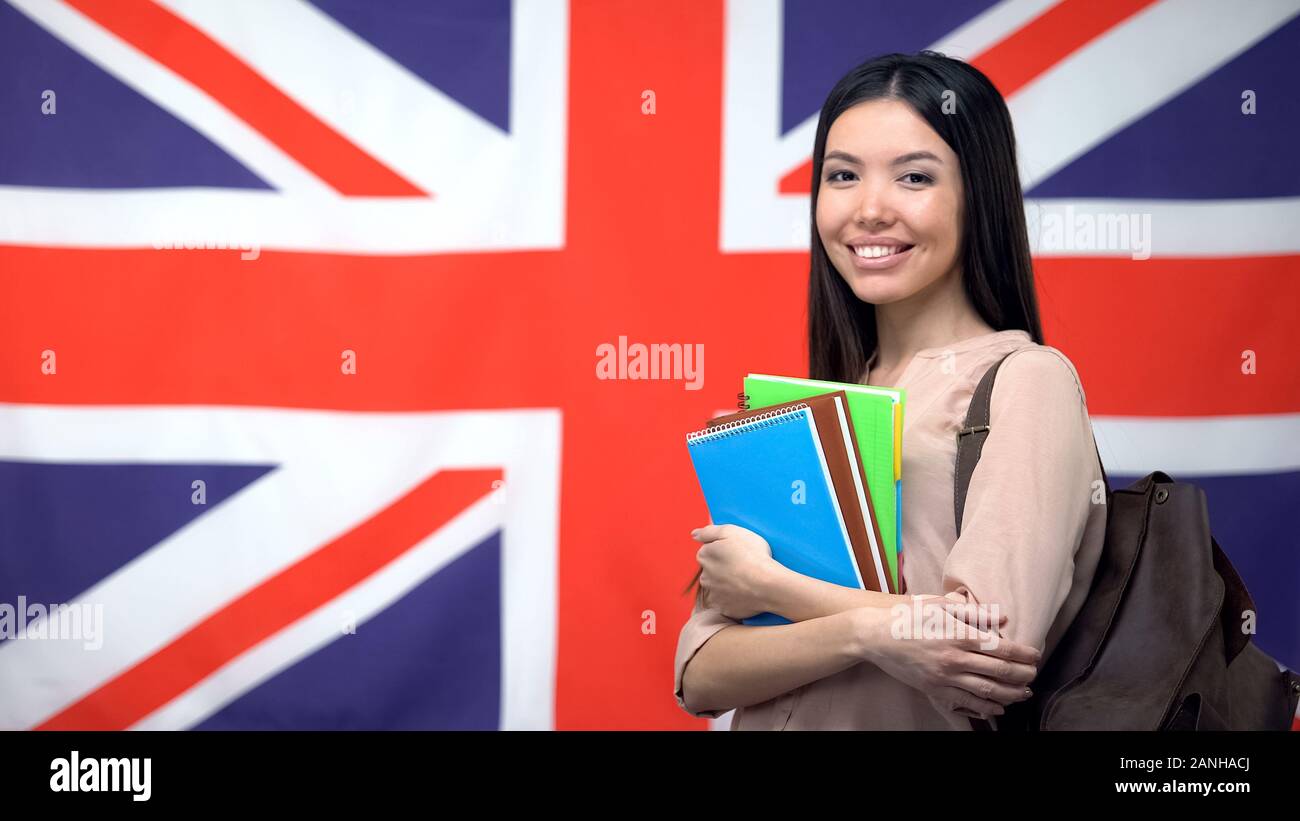 Allegra donna asiatica in piedi contro la bandiera britannica sfondo, studiare all'estero Foto Stock