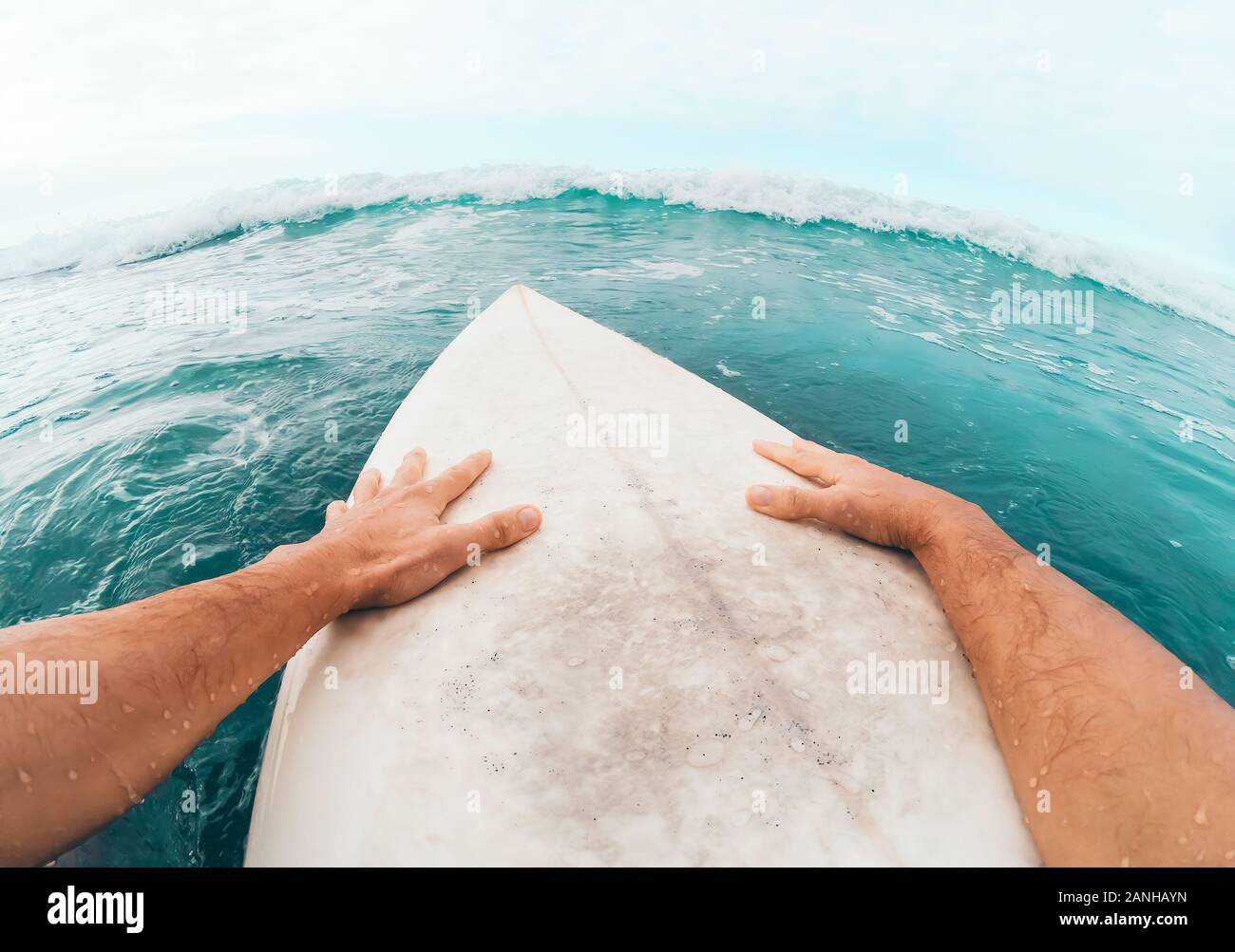 Giovane uomo avente fun surf sulle onde alte ocean - sportivo surfer facendo esercizi di addestramento su acqua blu Foto Stock