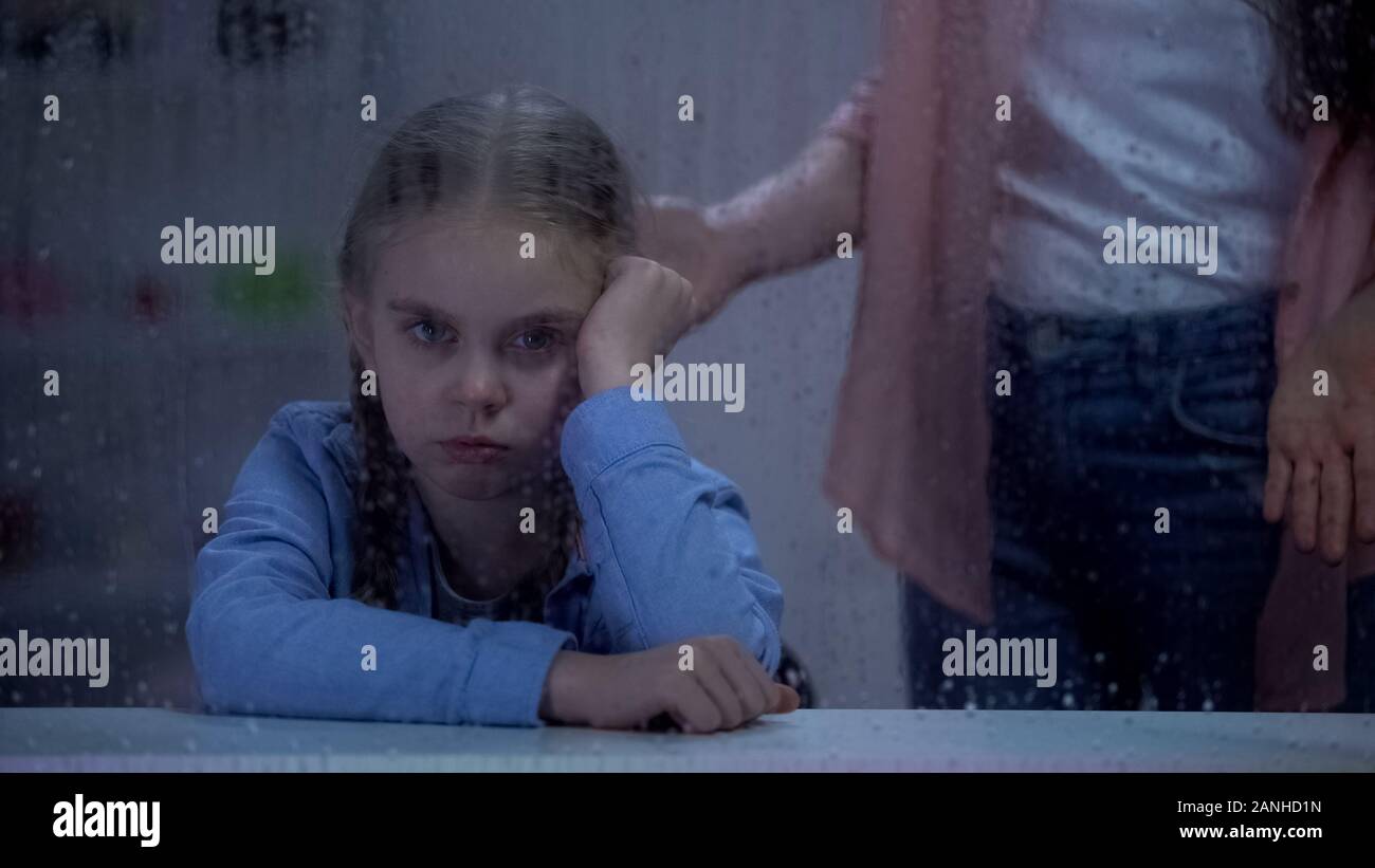 Madre scolding naughty little girl dietro la finestra piovosa, problema bambino nozione Foto Stock
