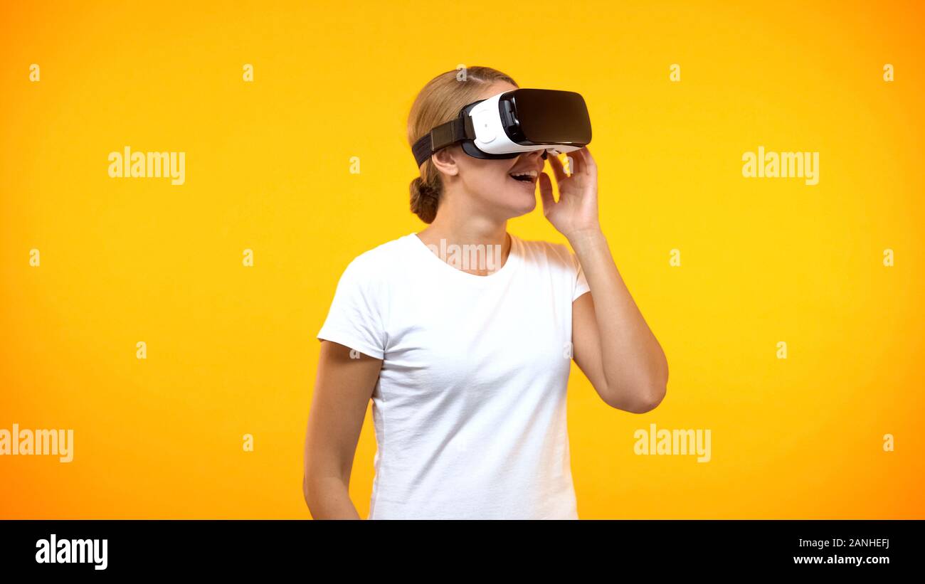 Excited donna giovane godendo di realtà virtuale che indossa la cuffia di gioco, intrattenimento Foto Stock