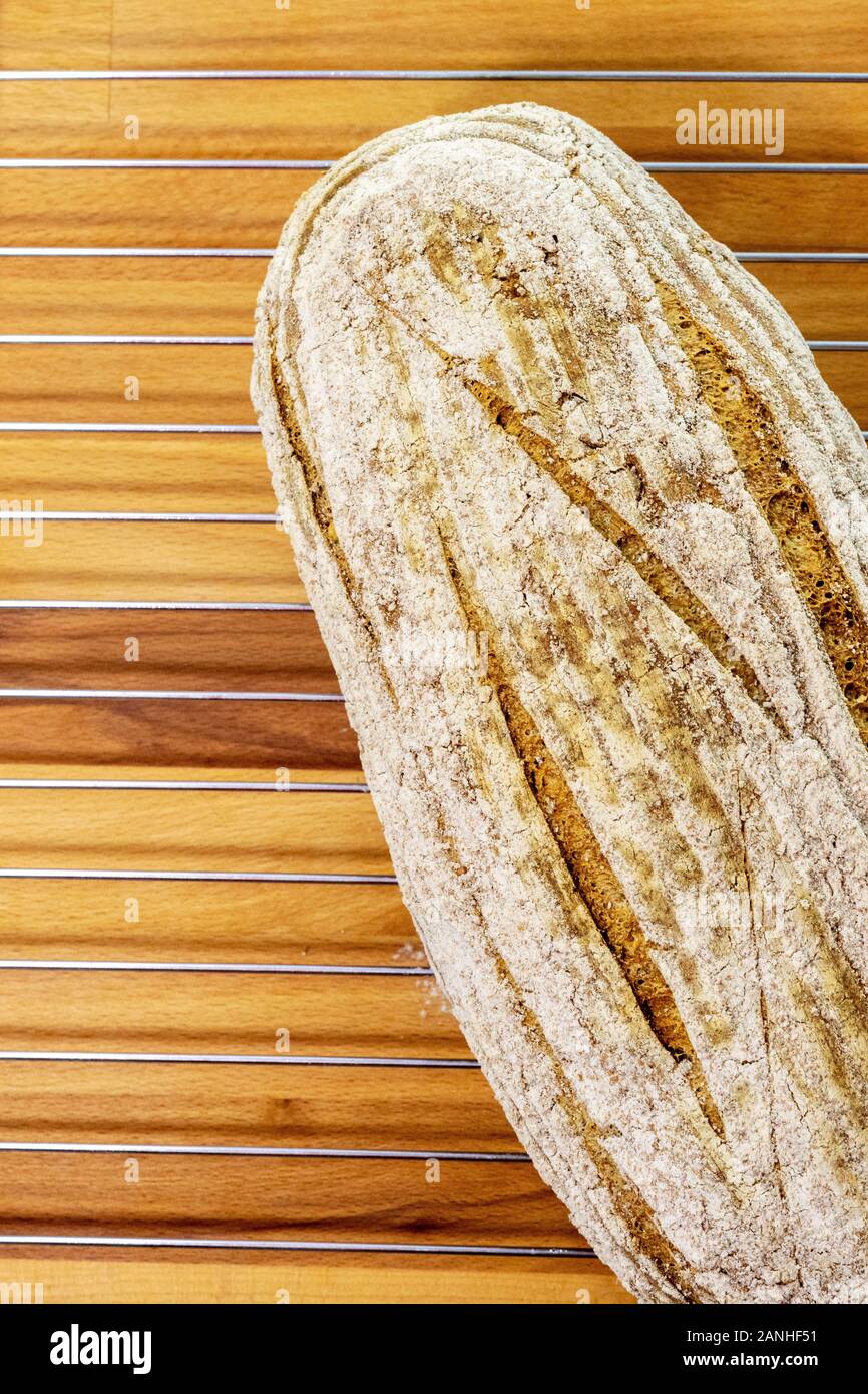 Pane appena sfornato white pagnotta di pane su una griglia di raffreddamento e tagliere di legno Foto Stock