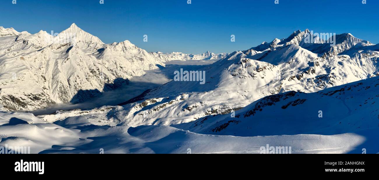 Importa la valle e le montagne nevose vista al tramonto paesaggio invernale sulle Alpi Svizzere nuvole di luce nella valle Foto Stock