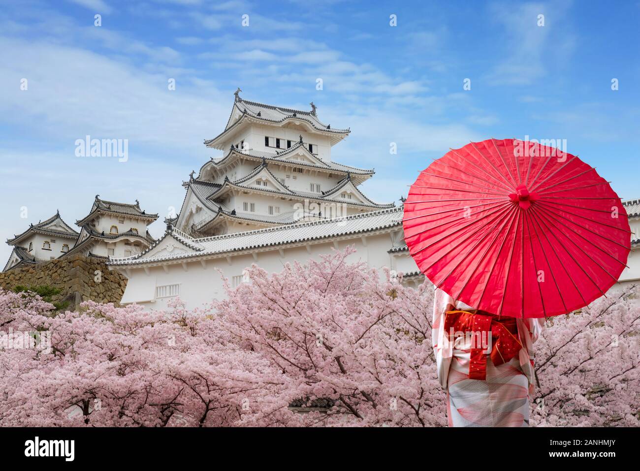 Asian giovane donna indossa il viaggiatore tradizionale giapponese kimono con ombrellone rosso dalla visita al celebre destinazione cherry blossom presso il castello di Himeji ne Foto Stock