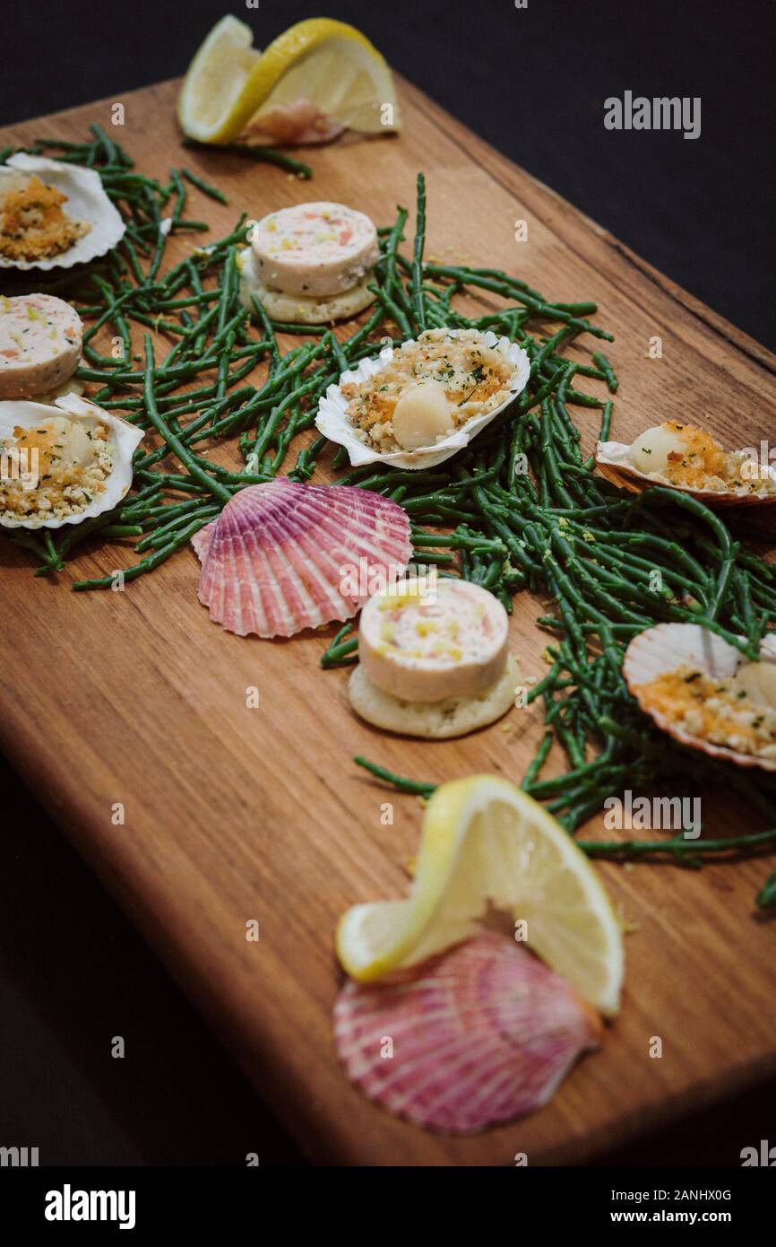 Piatto di pesce: Tartine servite su una tavola di legno con capesante e zeppe di samiro e limone. Vista dall'alto. Foto Stock