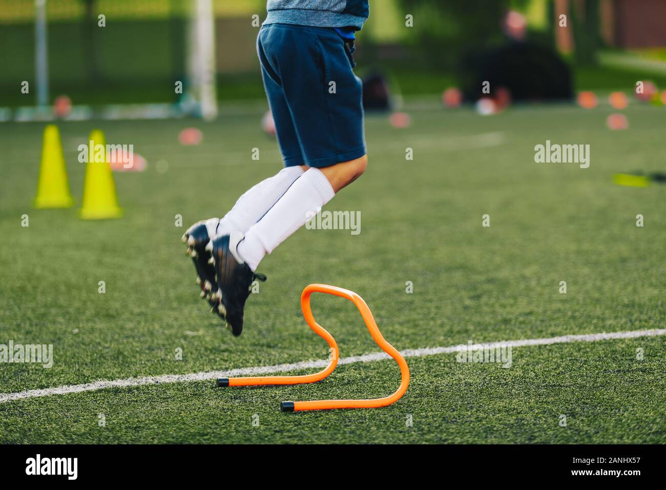 Giocatore di calcio salto sulla sessione di formazione del passo. Allenamento di calcio attrezzatura. Atleta saltando ostacoli sul campo di erba Foto Stock Giocatore di calcio salto sulla sessione di formazione del passo. Allenamento di calcio attrezzatura. Atleta saltando ostacoli sul campo di erba Foto Stock