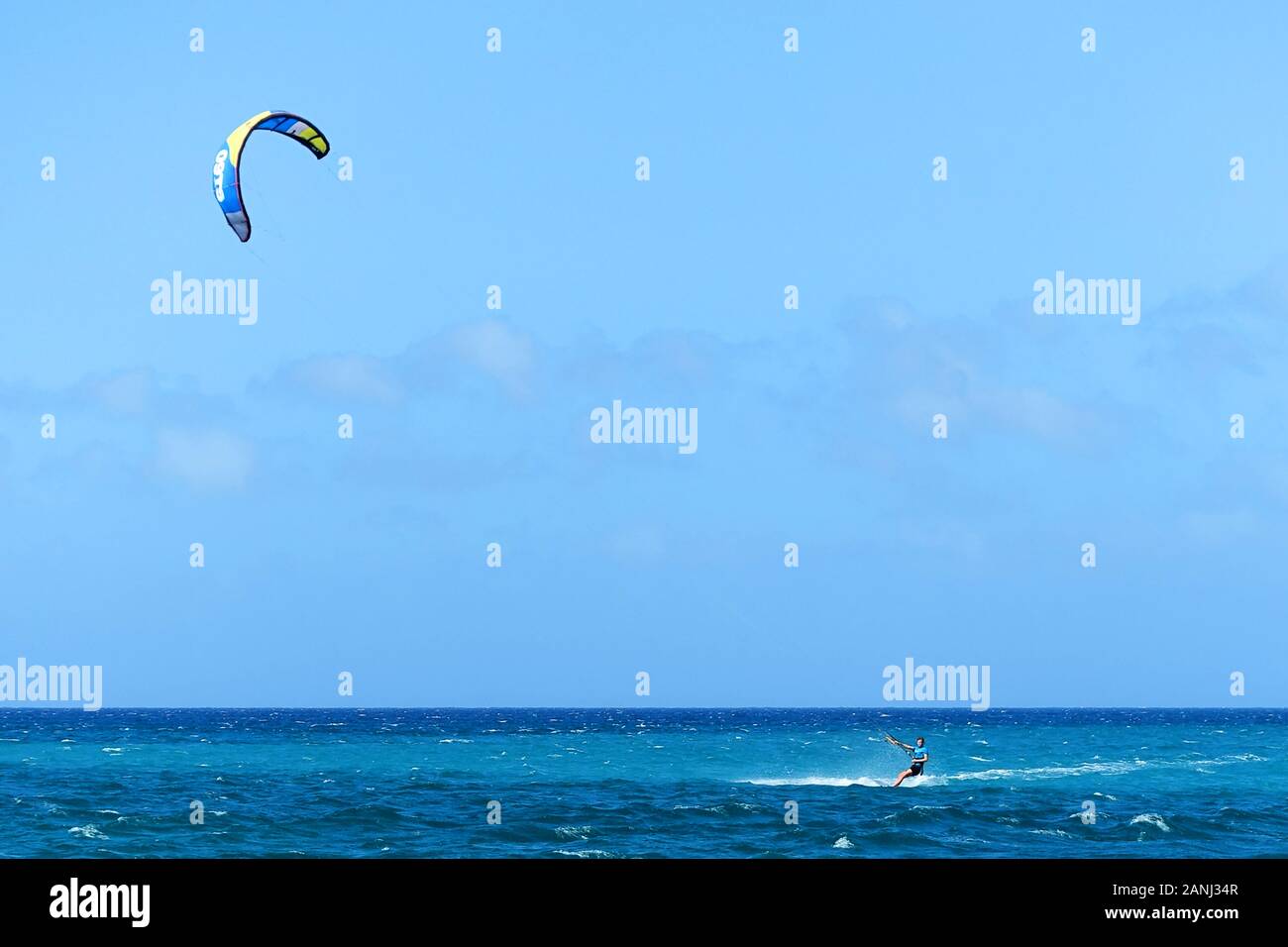 Un kiteboarder, nei Caraibi, che viaggia a velocità attraverso il mare con un vento alto lo sospinse in avanti con il suo aquilone di potenza Foto Stock