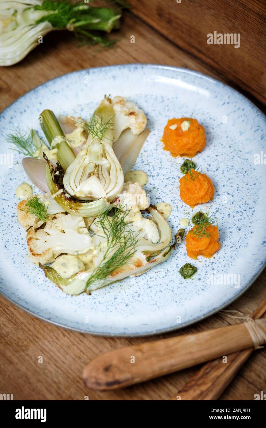 Piatto principale vegano: Bistecca di cavolfiore con finocchio e purea di carota. Sfondo in legno e vista dall'alto. Cibo vegetariano Foto Stock
