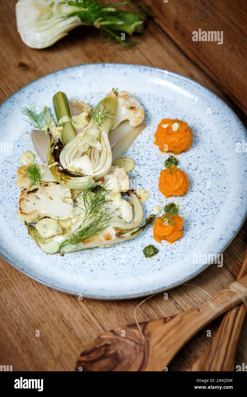 Piatto principale vegano: Bistecca di cavolfiore con finocchio e purea di carota. Sfondo in legno e vista dall'alto. Cibo vegetariano Foto Stock