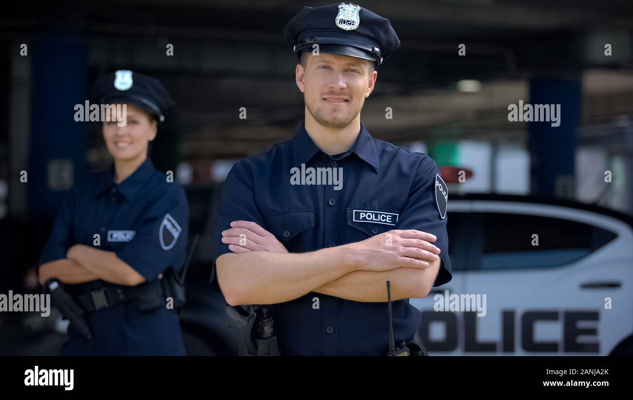 Tipo poliziotti sorridente in piedi vicino a una stazione di polizia, pronto ad aiutare, ordine Foto Stock