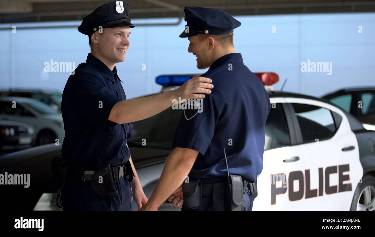 Allegro poliziotto saluto compagno di squadra contro auto, pronta per il pattugliamento, lavoro Foto Stock