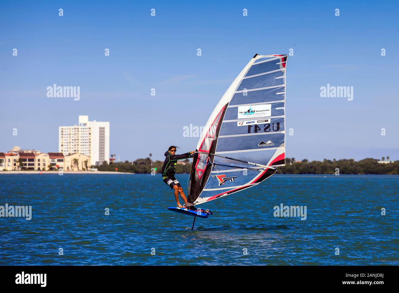 Un windsurf vola fuori dell'acqua nella parte anteriore del Ponte di Causeway nel porto di Clearwater. La temperatura è aumentata nella 80's impostazione vicino ad alta record per questo tempo di anno in Florida. Foto Stock