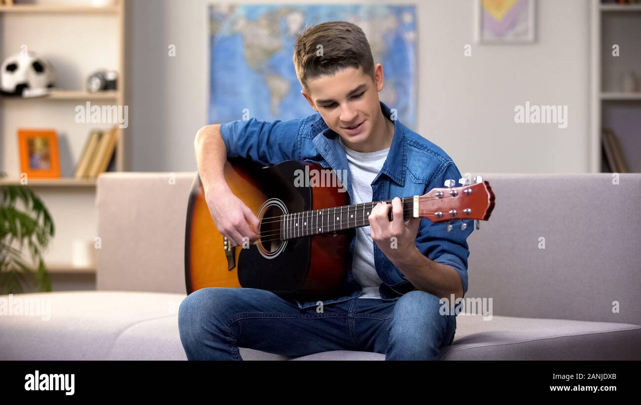 Allegro Caucasian adolescente suonando la chitarra, godendo di hobby preferito, tempo libero Foto Stock