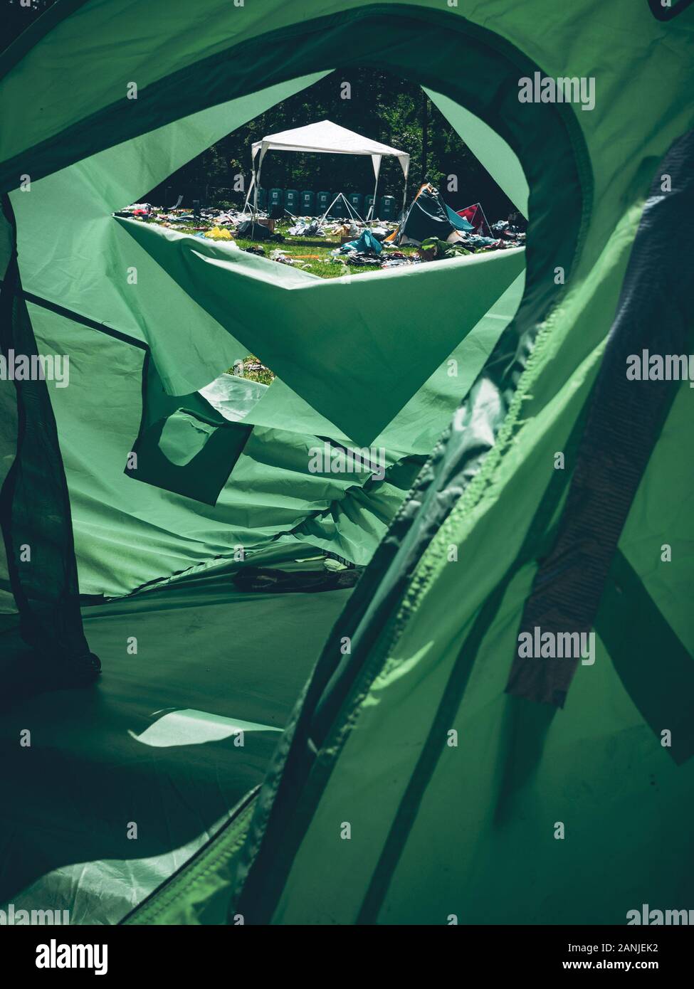 Guardare fuori da una tenda verde su un festival di musica con i rifiuti in tutto il luogo Foto Stock