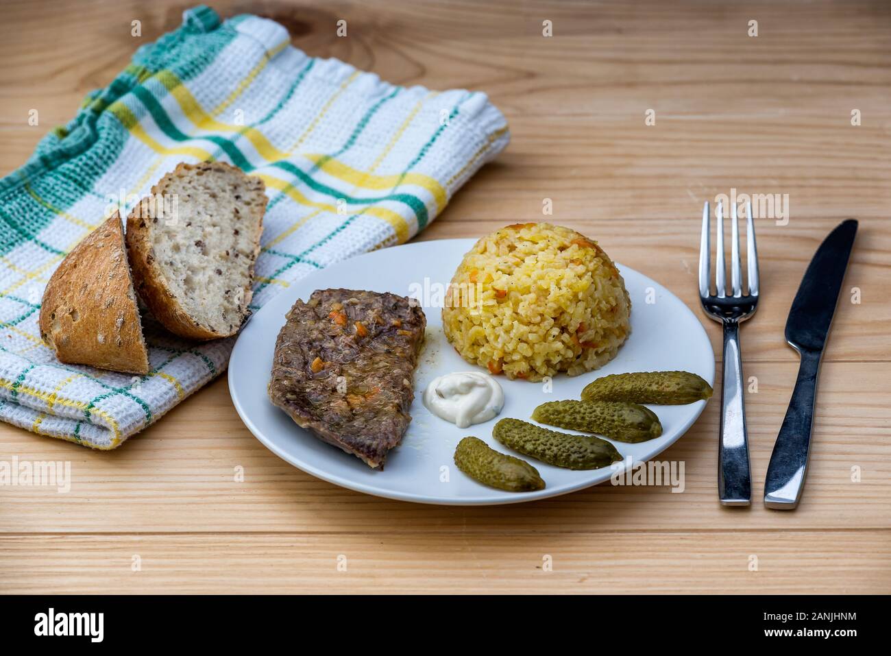 Preparate la bistecca di manzo con riso risotto, sottaceti e salsa su piastra bianca sul tavolo di legno sfondo Foto Stock