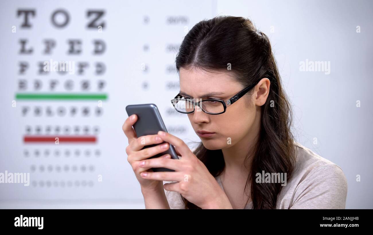 Donna in occhiali la digitazione sullo smartphone e moderne tecnologie font piccoli Foto Stock