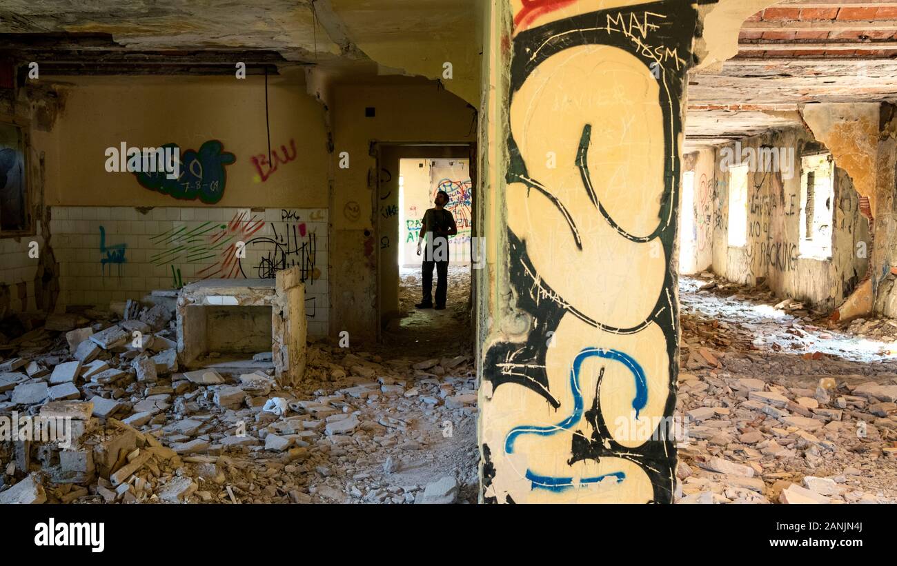 Escursionista che esplora l'interno della stazione ferroviaria abbandonata di Yera, vandalizzato e pieno di graffiti (Yera, Vega de Pas, Valles Pasiegos, Cantabria, Spagna) Foto Stock
