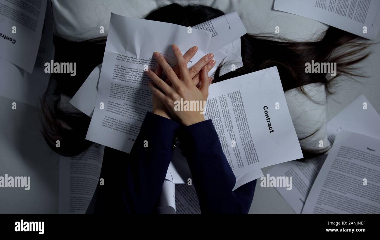 Il dipendente di sesso femminile che copre con sé documenti, disperato del carico di lavoro, burnout Foto Stock