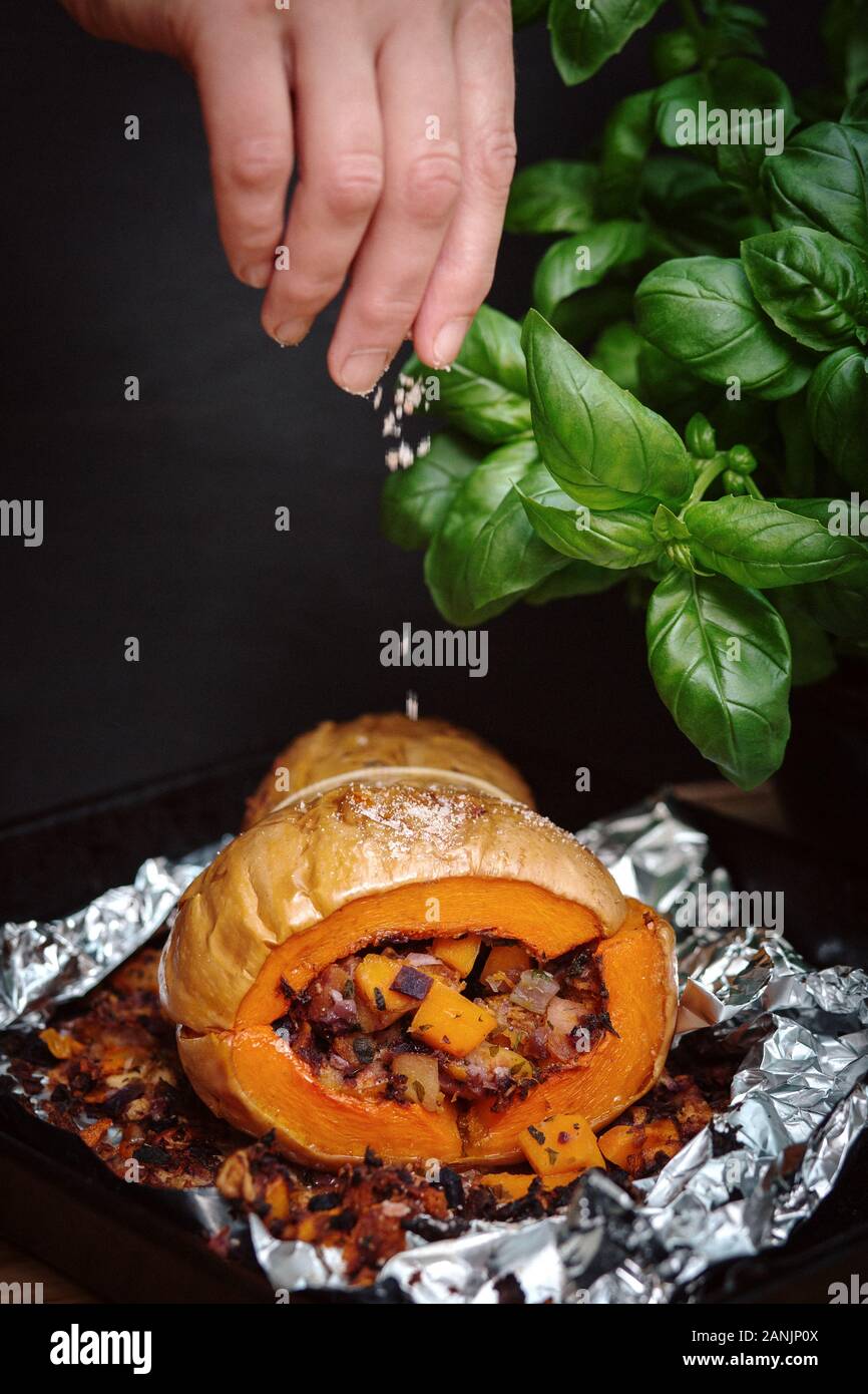 Zucca di Butternut ripiena arrosto con insalata di cavolo e ceci. Sano cibo vegano servito su un vassoio arancione con sfondo nero. Vista dall'alto / piatto Foto Stock